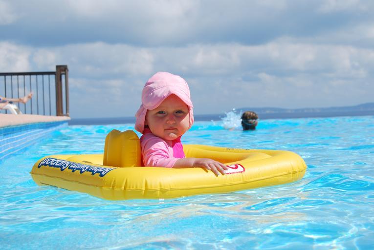 malá holčička v dětském plovacím kruhu se koupe v bazénu