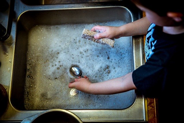 dítě pomáhá v kuchyni mýt nádobí